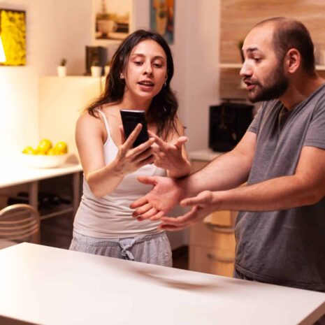 woman-pointing-phone-while-reading-messages-infidel-husband-while-having-disagreement-heated-angry-frustrated-offended-irritated-accusing-her-man-cheating (1)